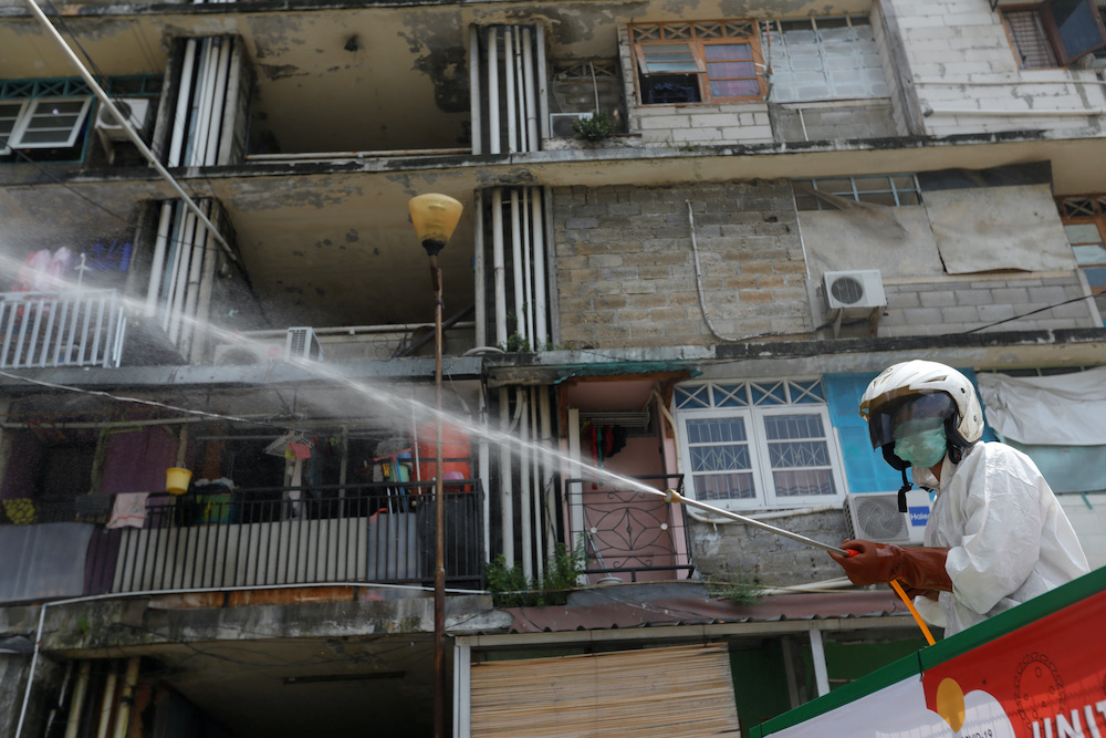 A Red Cross personnel wearing a protective suit sprays disinfectant in a densely populated neighbourhood area, amid the spread of the coronavirus disease (Covid-19) in Jakarta, Indonesia, April 4, 2020. u00e2u20acu201d Reutersnn