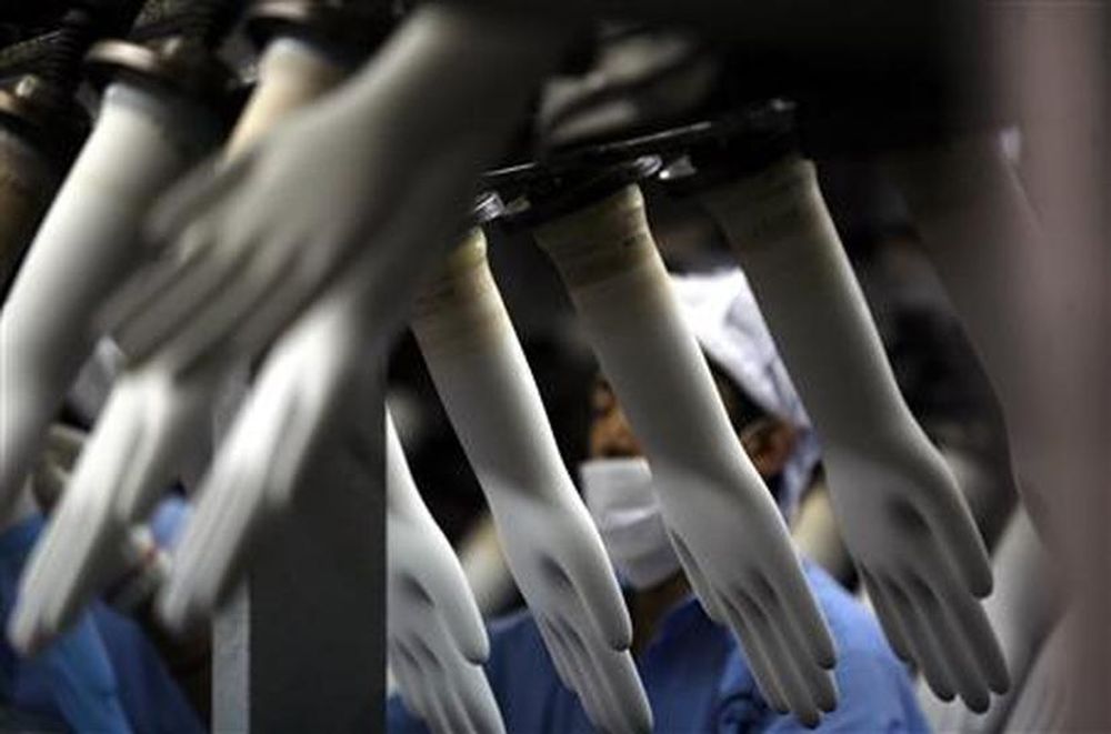 A worker collects rubber gloves at Top Gloveu00e2u20acu2122s factory in Klang, outside Kuala Lumpur, March 11, 2008. u00e2u20acu201d Reuters pic