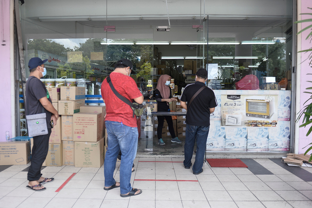 Customers line up outside of a bakery product supply shop to buy their needs during movement control order (MCO) in Shah Alam April 22, 2020. u00e2u20acu201d Picture by Miera Zulyana