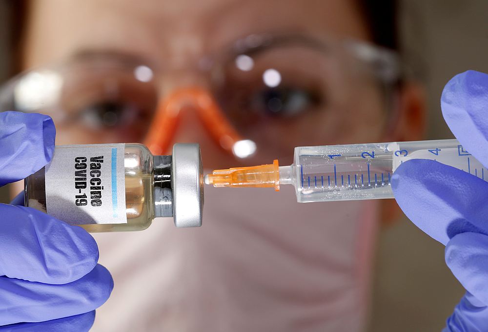 A woman holds a small bottle labbelled with a 'Vaccine Covid-19' sticker and a medical syringe in this illustration taken April 10, 2020. u00e2u20acu201d Reuters pic