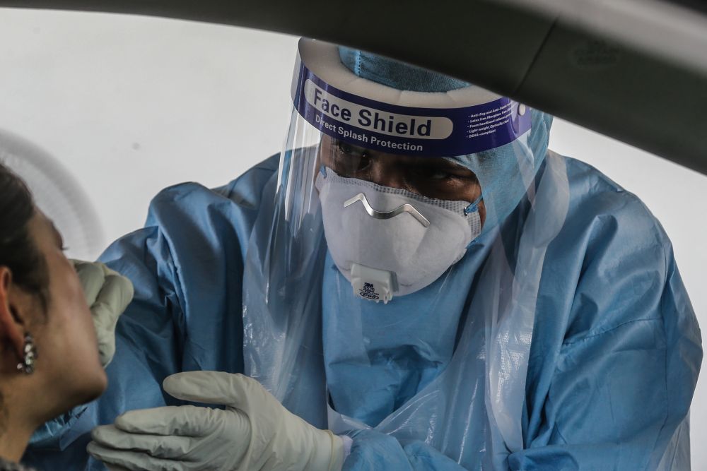 A health worker swabs a driveru00e2u20acu2122s mouth at a drive-through testing site for Covid-19 at KPJ Ampang Puteri, April 6, 2020. u00e2u20acu201d Picture by Firdaus Latif