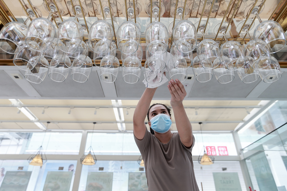 A bar worker in Changkat Tunku cleans the wine glasses before dine-in operations start on May 4. u00e2u20acu201d Picture by Ahmad Zamzahuri