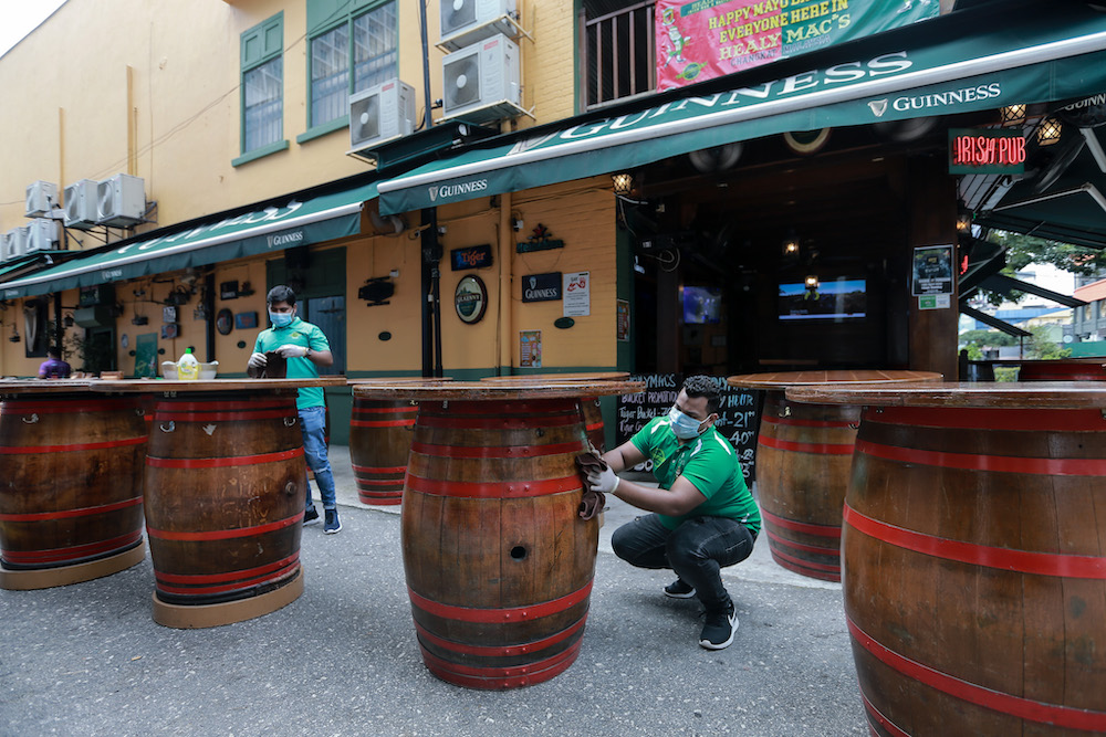 A bar worker in Changkat Tunku cleans the tables before dine-in operations start on May 4. u00e2u20acu201d Picture by Ahmad Zamzahuri