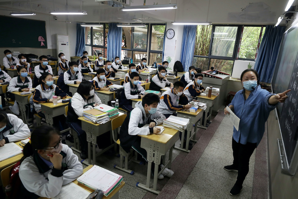 A teacher and senior high school students wearing face masks are seen inside a classroom on their first day of returning to campus following the coronavirus disease (Covid-19) outbreak, in Wuhan  May 6, 2020. u00e2u20acu201d China Daily handout via Reuters