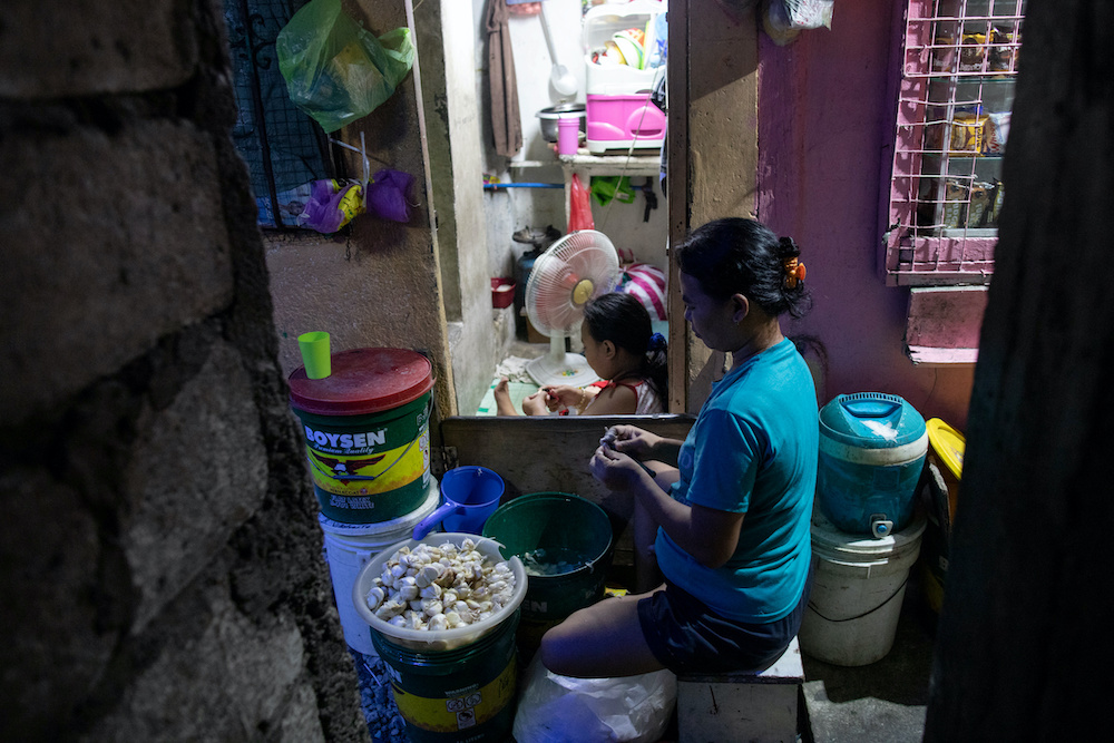 Maribel Ballena, 28, peels buckets of garlic with her daughter outside their shanty home, in the slum area of Tondo, Manila May 6, 2020. u00e2u20acu201d Reuters pic
