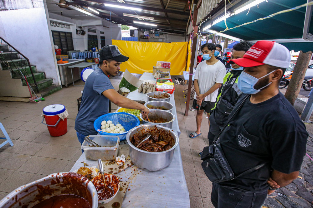 不少食客到位于甘榜巴鲁的著名椰浆饭餐厅，外带美味的食物。-Hari Anggara摄-