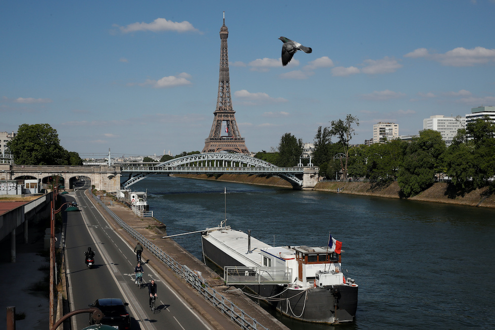 People ride bicycles on a bike path on the banks of the river Seine with the Pont Rouelle bridge and the Eiffel tower in the background in Paris during the outbreak coronavirus disease in France, May 14, 2020. u00e2u20acu201d Reuters picnnn