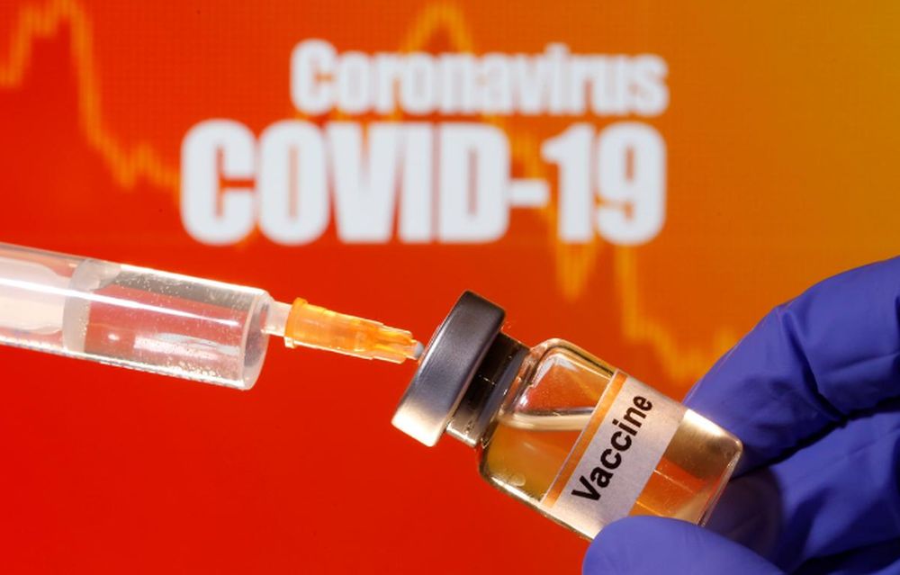 A small bottle labelled with a u00e2u20acu02dcVaccineu00e2u20acu2122 sticker is held near a medical syringe in front of displayed u00e2u20acu02dcCoronavirus Covid-19u00e2u20acu2122 words in this illustration taken April 10, 2020. u00e2u20acu201d Reuters pic