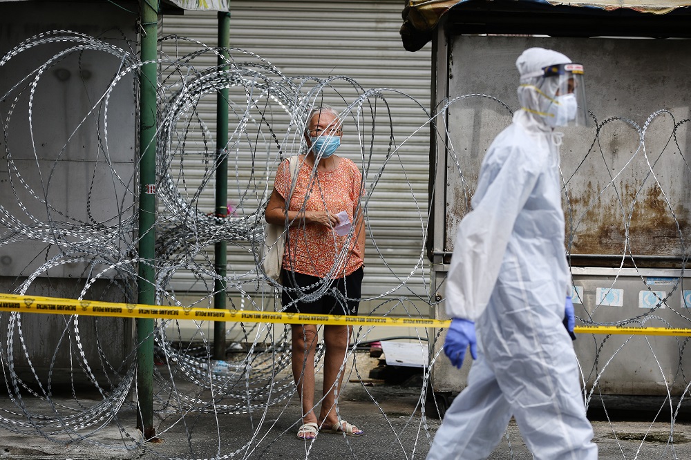 A woman walks past barbed wire fencing in Pudu, Kuala Lumpur May 19, 2020. u00e2u20acu2022 Picture by Yusof Mat Isa