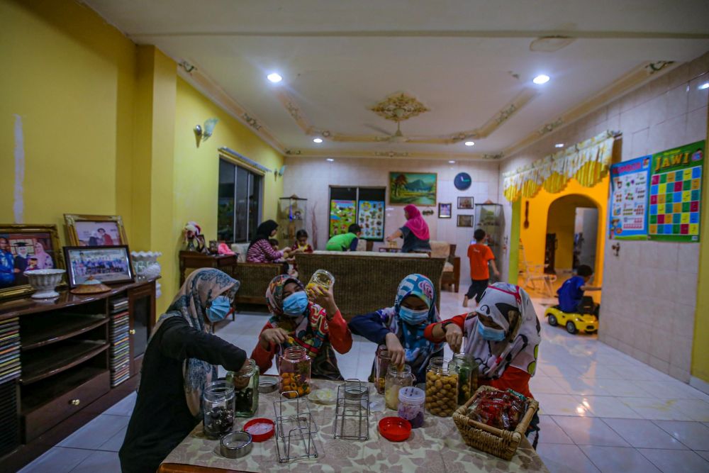 A group of women in the family prepare jars of cookies at home in Kampung Changkat, Gombak on the eve of Hari Raya Aidilfitri May 23, 2020. u00e2u20acu201d Picture by Hari Anggara