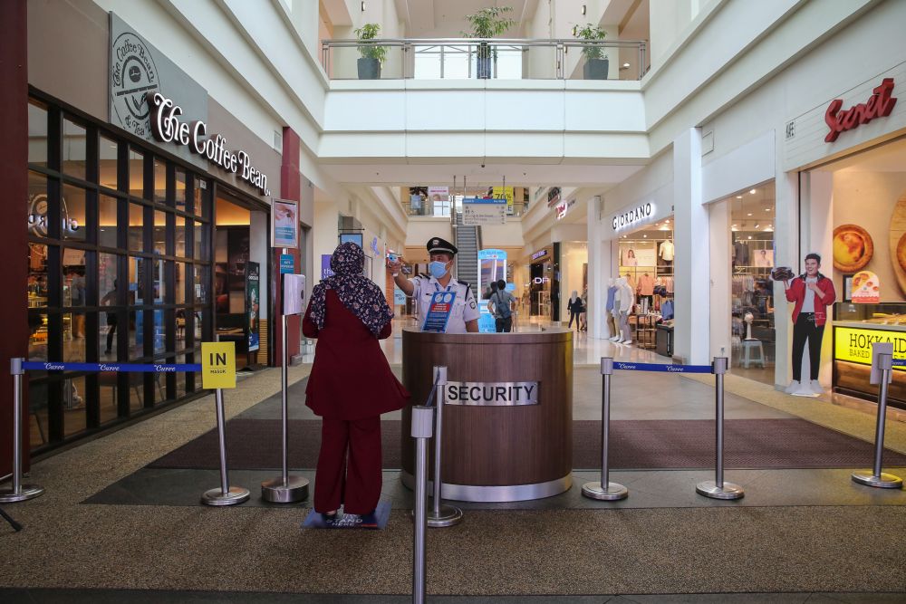 A security personnel checks a patronu00e2u20acu2122s temperature at The Curve shopping mall entrance in Petaling Jaya May 28, 2020. u00e2u20acu201d Picture by Yusof Mat Isa