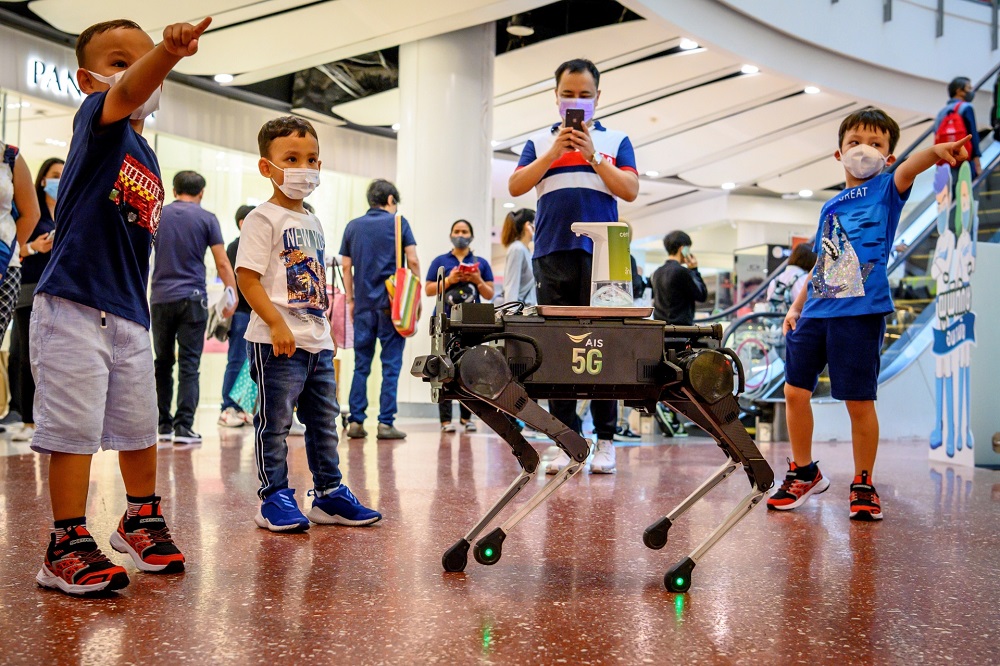 Children play with a 5G K9 robot distributing hand sanitiser to visitors in a shopping mall in Bangkok. u00e2u20acu201d AFP pic
