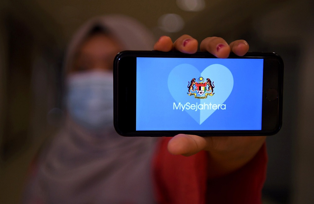 A woman holds up a phone displaying the MySejahtera app in Kuala Lumpur May 6, 2020. u00e2u20acu201d Bernama pic