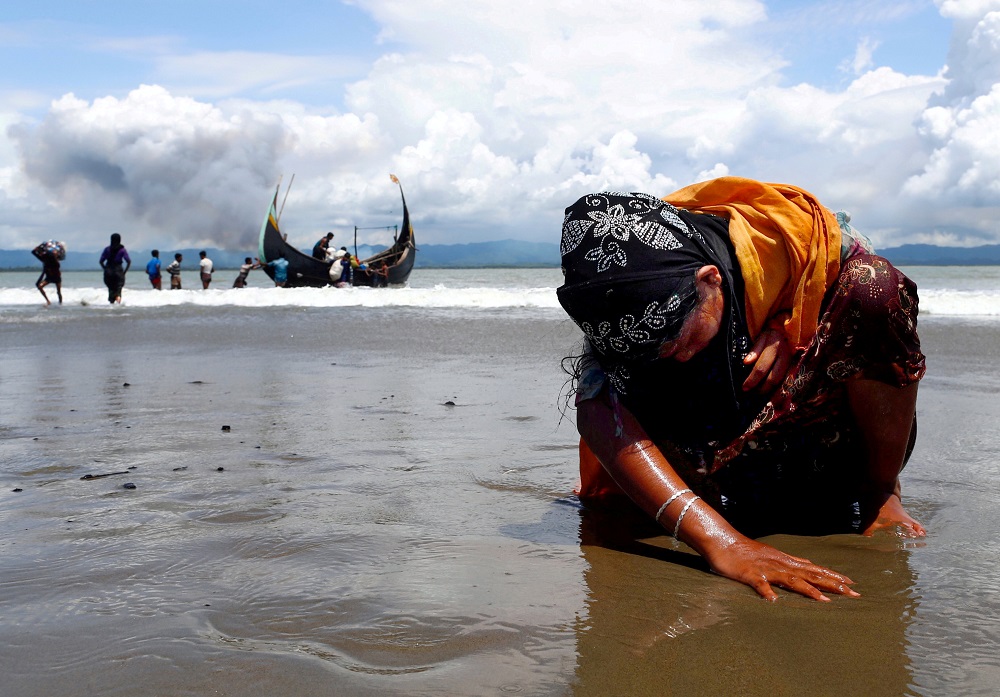 An exhausted Rohingya refugee woman touches the shore after crossing the Bangladesh-Myanmar border, September 11, 2017. u00e2u20acu2022 Reuters file pic