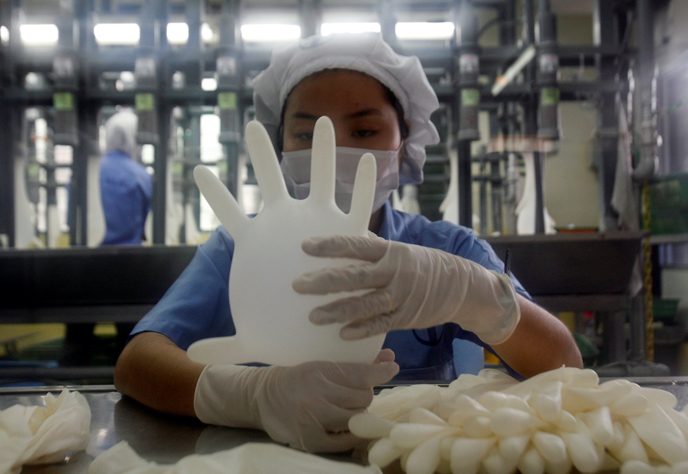 A worker carries out a test on a glove at a Top Glove factory outside Kuala Lumpur June 25, 2009. u00e2u20acu201d Reuters pic 