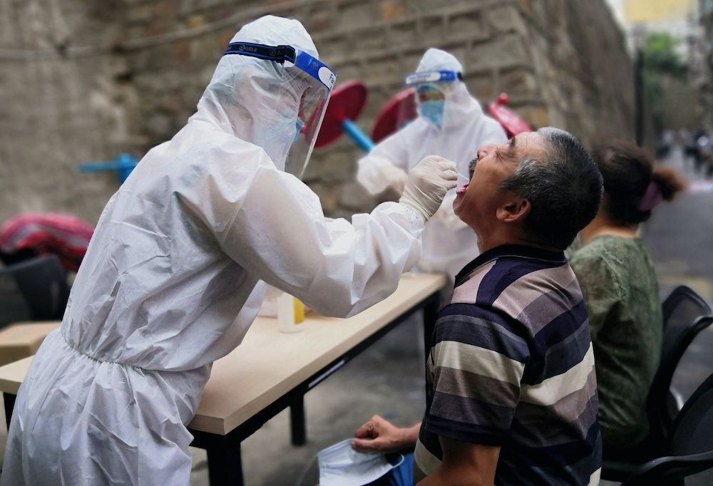 A medical worker collects a swab from a man to conduct free nucleic acid tests for residents in the residential compound, after new cases of Covid-19 were found in Urumqi, Xinjiang province, China July 19, 2020. u00e2u20acu201d cnsphoto handout via Reuters