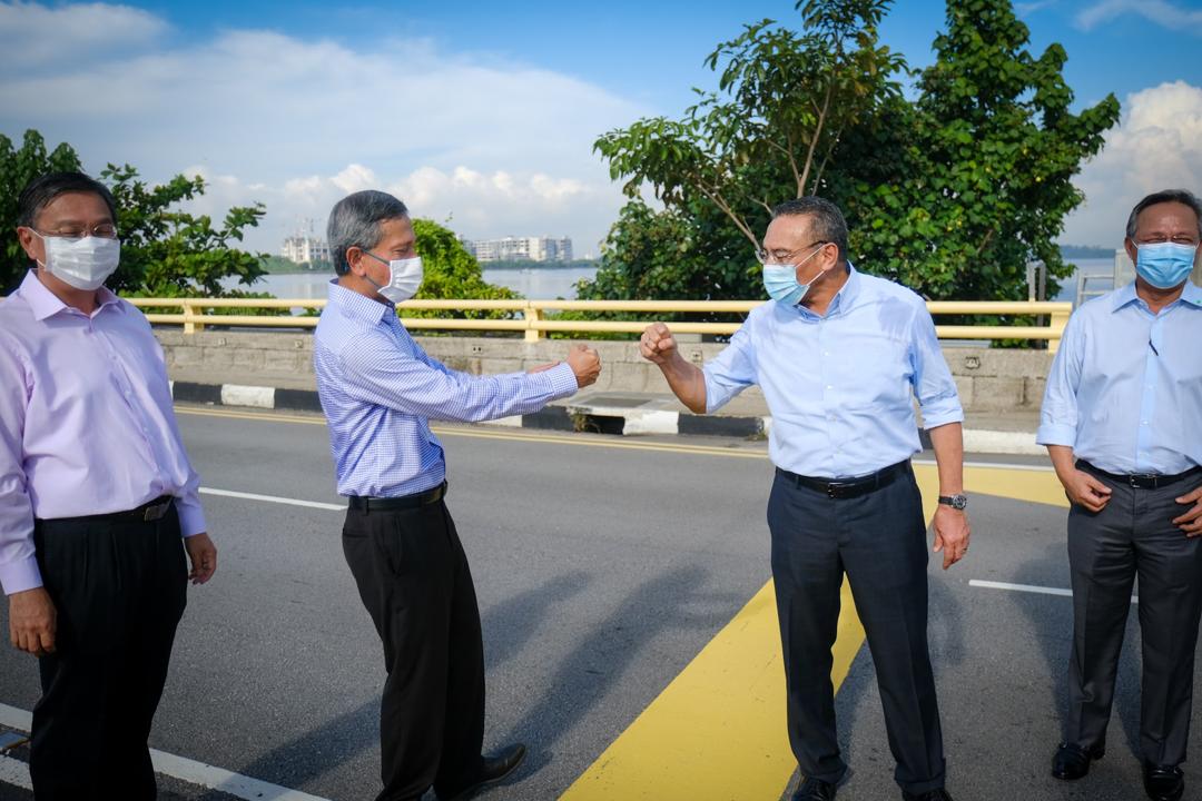 Foreign Minister Datuk Seri Hishamuddin Hussein (second from right) and Singapore Foreign Affairs Minister Dr Vivian Balakrishnan bump fists after a meeting at the Johor-Singapore Causeway near Johor Baru July 26, 2020. u00e2u20acu201d Picture courtesy of Wisma Putra