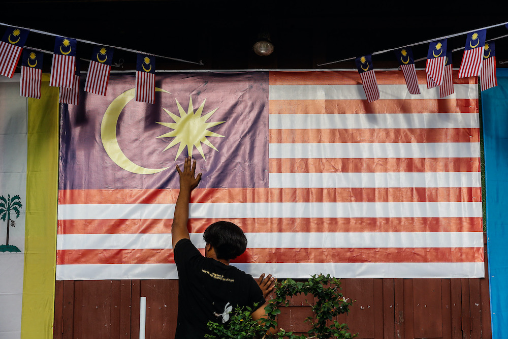Ahmad Shazli Hashim places a large Malaysian flag in front of the house at Kg Perlis, Balik Pulau August 15, 2020. u00e2u20acu201d Picture by Sayuti Zainudin