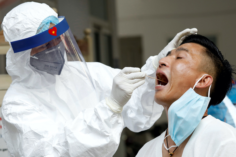 A medical specialist wearing a protective suit collects a swab sample from a traveller who has returned from Da Nang, at a testing center for coronavirus disease (Covid-19) in Hanoi, Vietnam August 10, 2020. u00e2u20acu201d Reuters pic