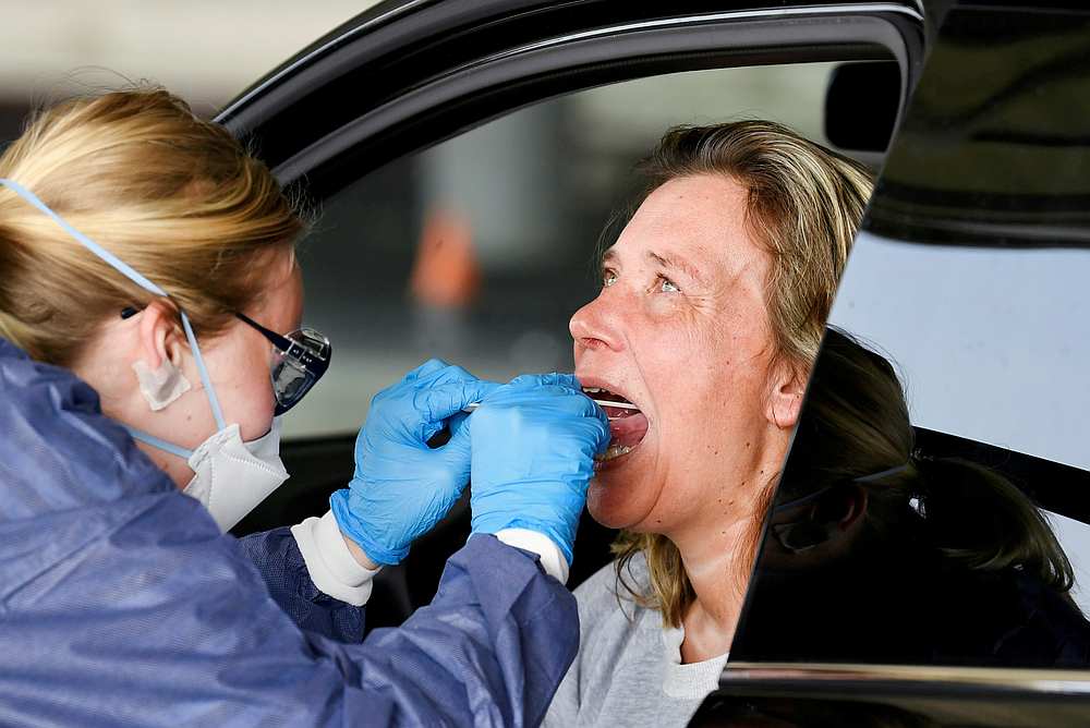 A medical staff takes Covid-19 test samples of a woman during drive-thru virus testing, on a converted ice rink, in Alkmaar, Netherlands April 8, 2020. u00e2u20acu201d Reuters pic