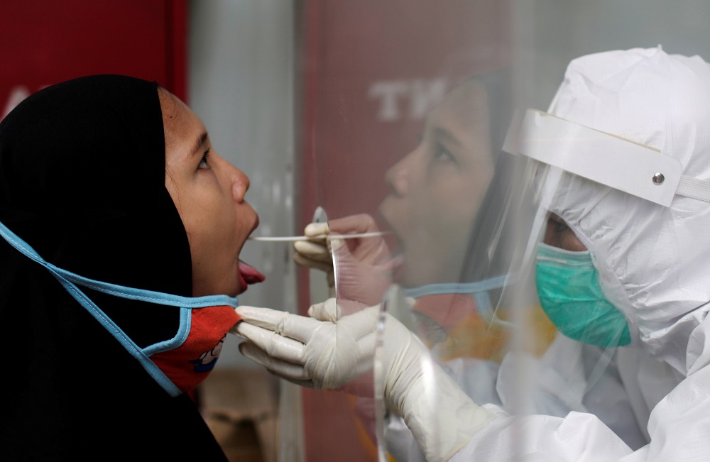 A healthcare worker wearing protective gear collects a swab sample to be tested for the coronavirus disease (Covid-19), at a local health facility in Jakarta September 29, 2020. u00e2u20acu201d Reuters pic