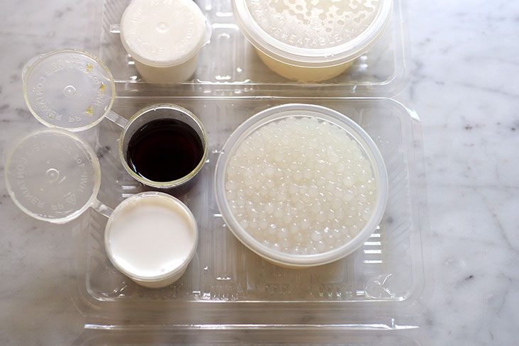 每套布丁都装在一个小塑料杯中，而椰奶和椰糖浆则分开装在小容器中。