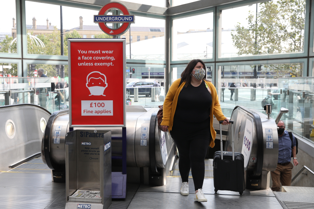 A woman wearing a protective face covering passes a poster warning of fines for not wearing face coverings as she steps off the escalator at St Pancras station in London September 11, 2020. u00e2u20acu201d AFP pic 