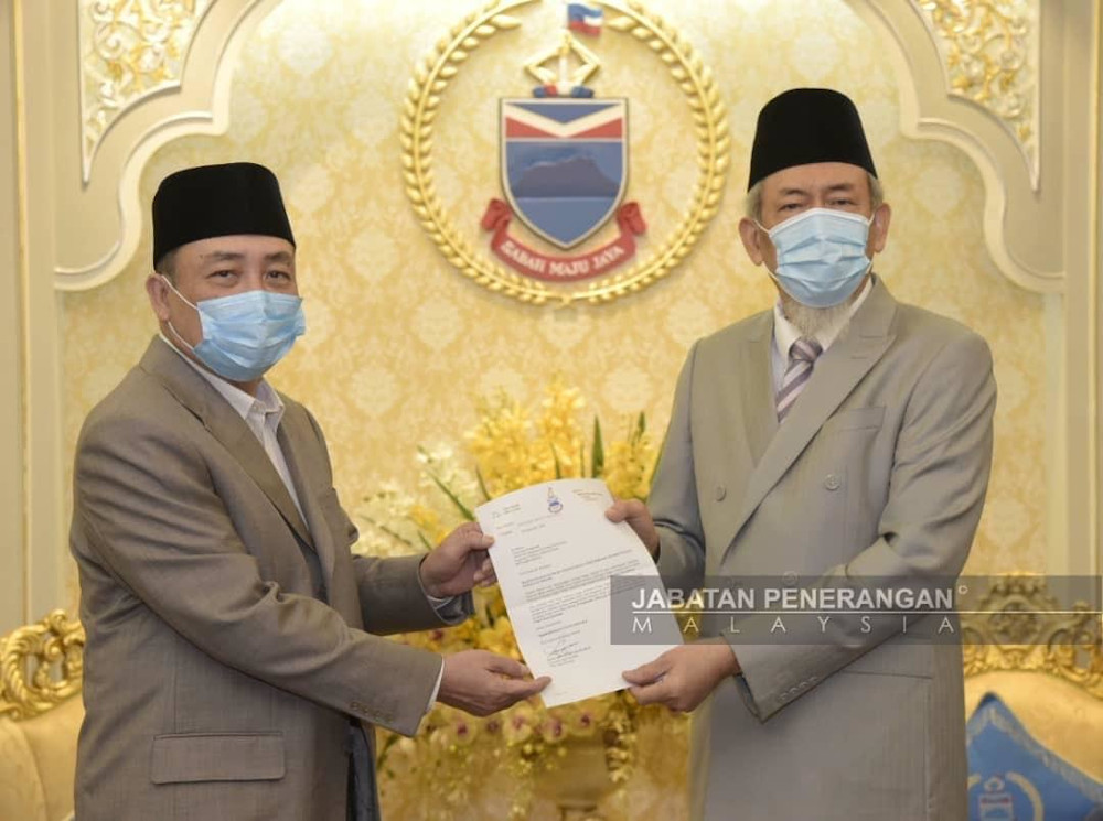 Tun Juhar (right) hands Hajii (left) a letter to take his oath as the 16th Sabah chief minister in the Istana Negeri Sabah today u00e2u20acu201d Picture courtesy of Malaysian Information Department
