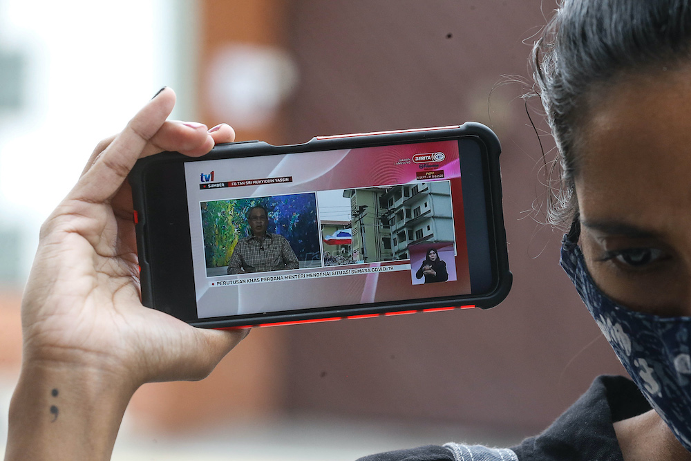 A woman listens to the special announcement by Prime Minister Tan Sri Muhyiddin Yassin on her smartphone, October 6, 2020. u00e2u20acu201d Picture by Sayuti Zainudin