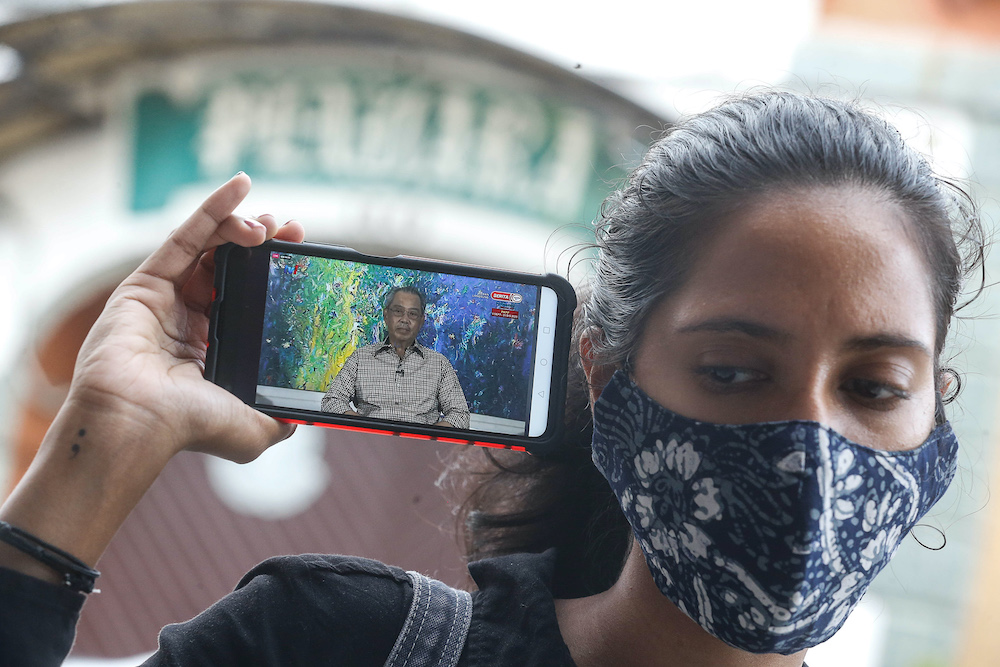 A woman listens to the special announcement by Prime Minister Tan Sri Muhyiddin Yassin on her smartphone, October 6, 2020. u00e2u20acu201d Picture by Sayuti Zainudin
