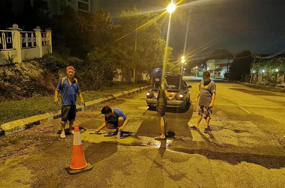 Rather than whine about the inaction of authorities, a group of Bercham residents in Ipoh has taken upon themselves to refill potholes in the area. u00e2u20acu201d Courtesy photo from Phuah Tuck Jun