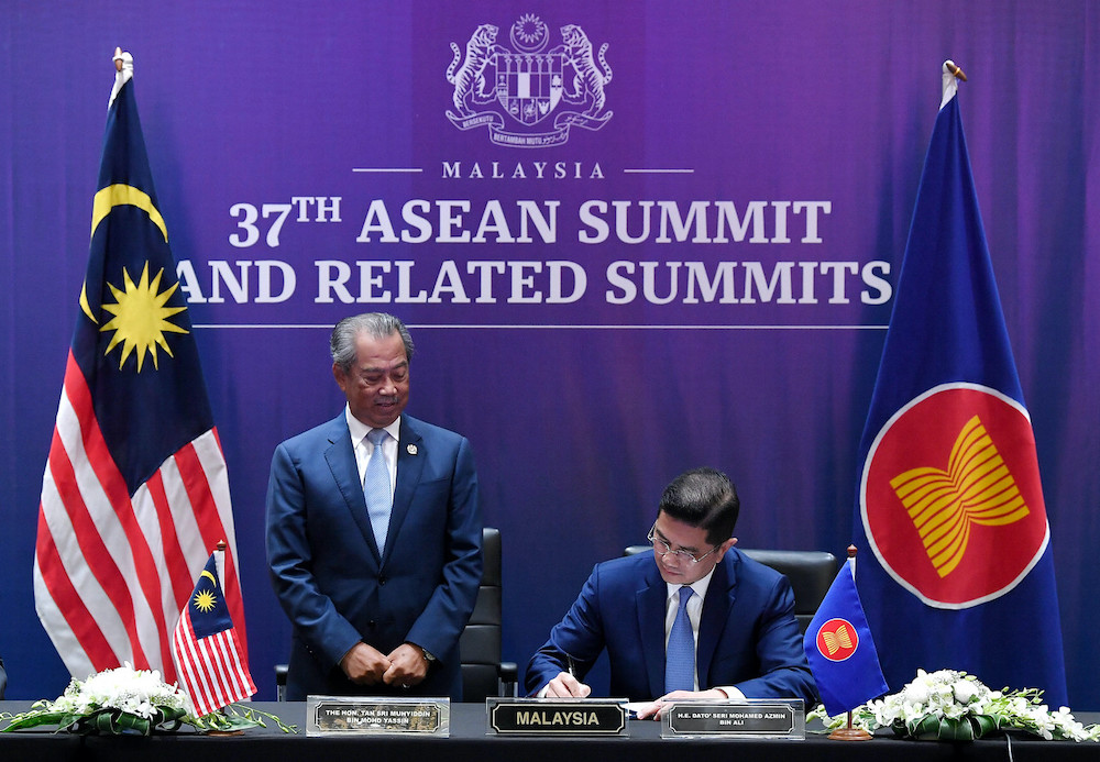 Prime Minister Tan Sri Muhyiddin Yassin looks on as International Trade and Industry Minister Datuk Seri Mohamed Azmin Ali signs the RCEP Agreement, November 15, 2020. u00e2u20acu201d Bernama pic