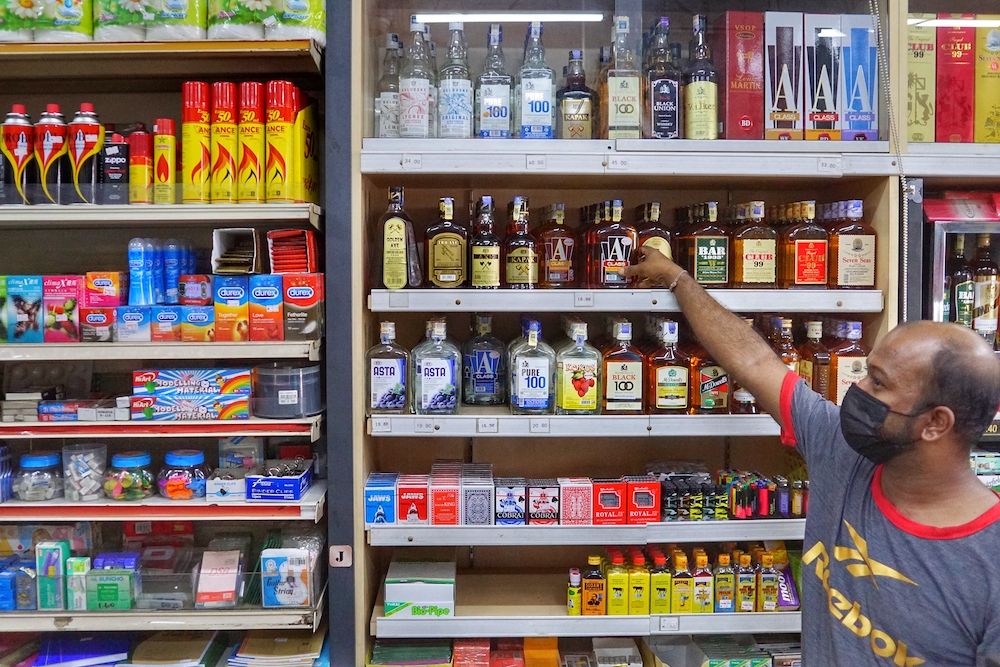 An employee stands in front of liquor bottles in a convenience shop near Sentul November 19, 2020. u00e2u20acu201d Picture by Ahmad Zamzahuri