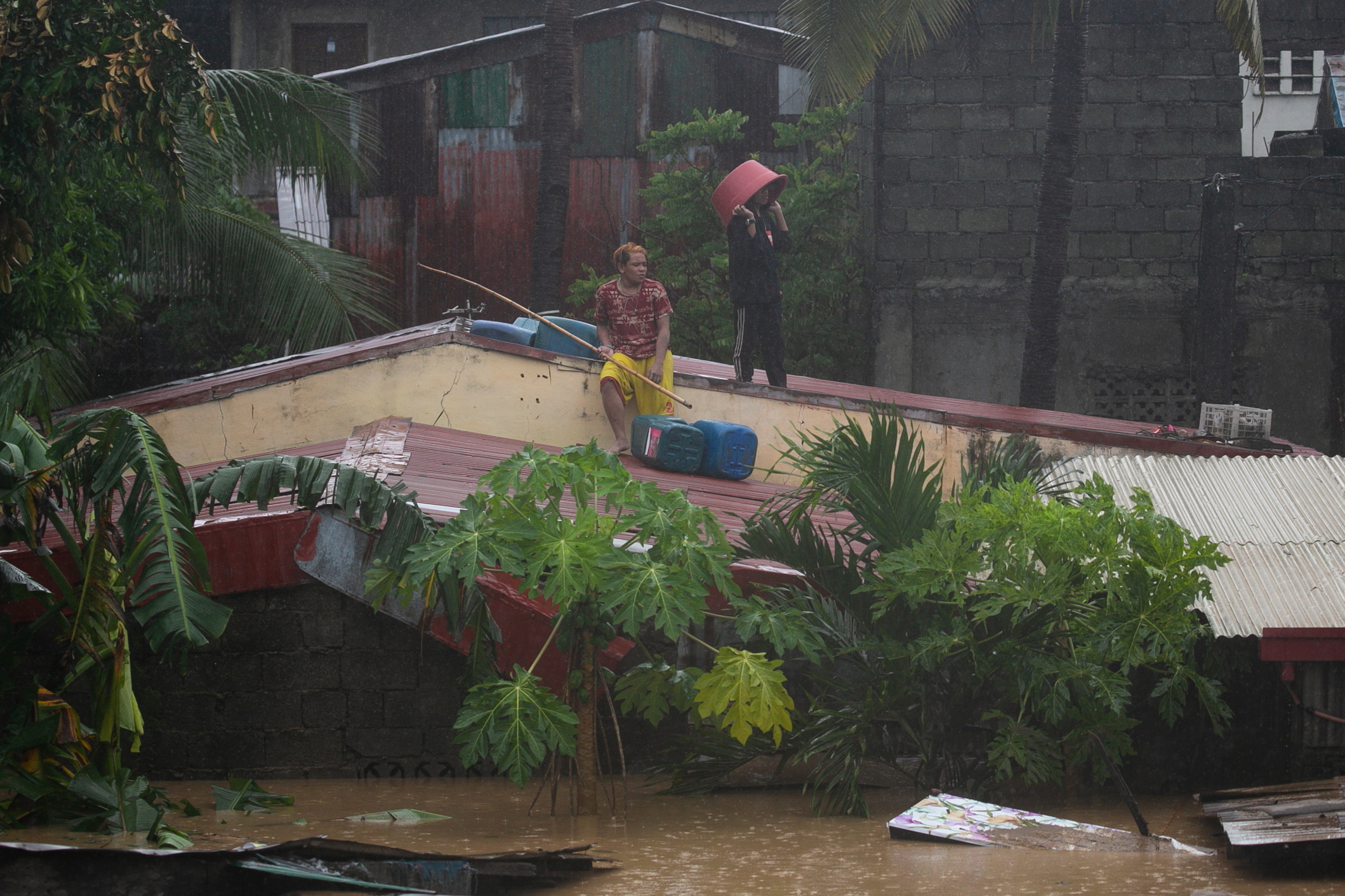 马尼拉东部的部份郊区，很多房子都被洪水淹到只看见屋顶，不少民众被困在屋顶上等待救援。-路透社-