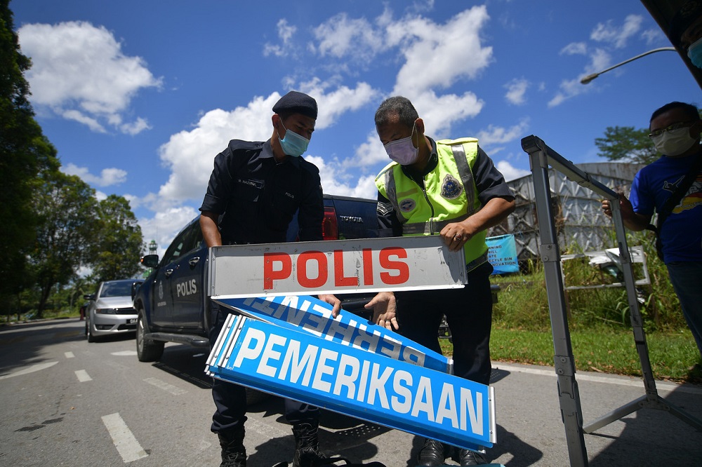 Police personnel set up a road block at the main entrance to Kampung Haji Baki following the enhanced movement control order at the area, in Kuching October 28, 2020. u00e2u20acu201d Bernama pic 