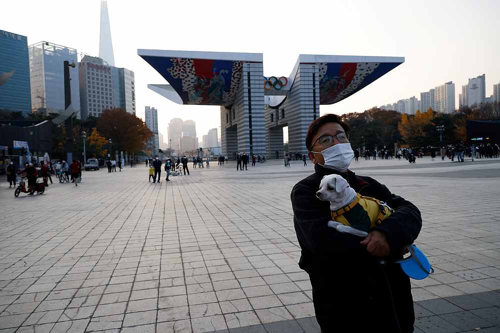 A man holding a pet dog takes a walk amid the Covid-19 pandemic at a park in Seoul, South Korea November 13, 2020. u00e2u20acu201d Reuters pic