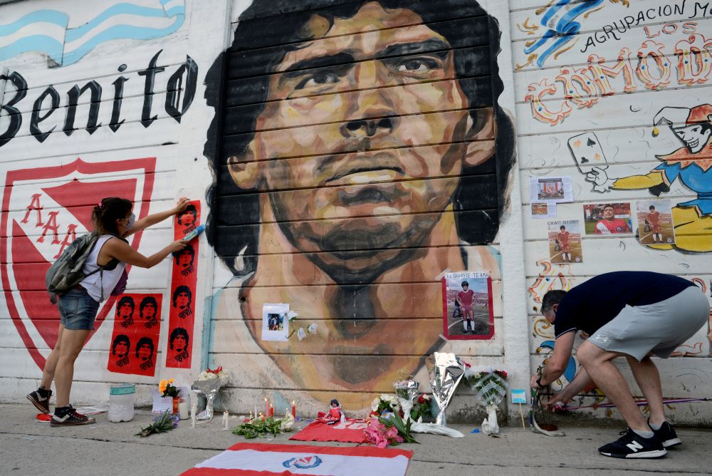 民众前往布宜诺斯艾利斯的马拉多纳体育场，在足坛传奇马拉多纳的肖像画前献花和纪念品悼念一代球王。-路透社-