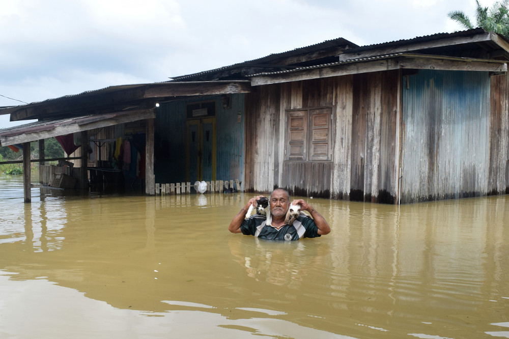 Zakaria Ismail, 71 carries his pet cats that were trapped in his house after heavy rain continued in Kampung Nyatoh, Penarik in Terengganu December 4, 2020. u00e2u20acu201d Bernamann