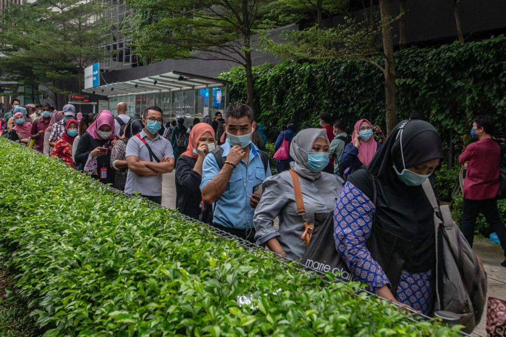 People wearing face masks queue at a bus stop in Kuala Lumpur December 18, 2020. u00e2u20acu201d Picture by Firdaus Latif