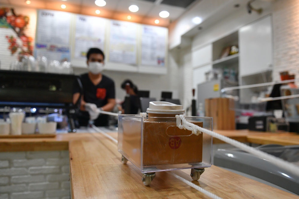 咖啡店店员把咖啡放在拉绳小车内“运”到客人面前。-图摘自那一年我们在曼谷-曼谷帮脸书-