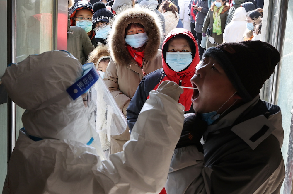 A medical worker in protective suit collects a swab from a resident during a mass nucleic acid testing following a recent Covid-19 outbreak in Shijiazhuang January 6, 2021. u00e2u20acu201d China Daily via Reuters