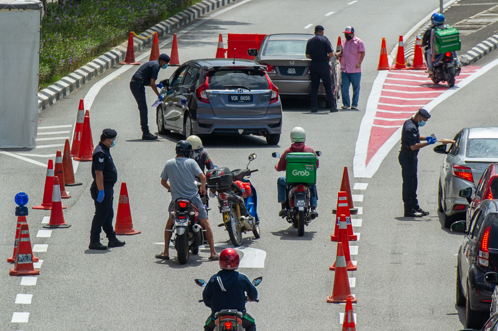 Police officers conducting checks at a roadblock in Jalan Kuching, Kuala Lumpur January 31, 2021. u00e2u20acu201d Picture by Shafwan Zaidon 