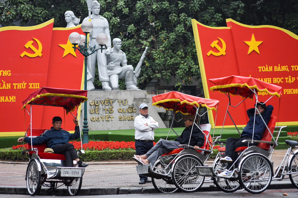 People wait for customers next to a poster of the 13th National Congress of the Communist Party of Vietnam in Hanoi, Vietnam January 25, 2021. u00e2u20acu201d Reuters pic