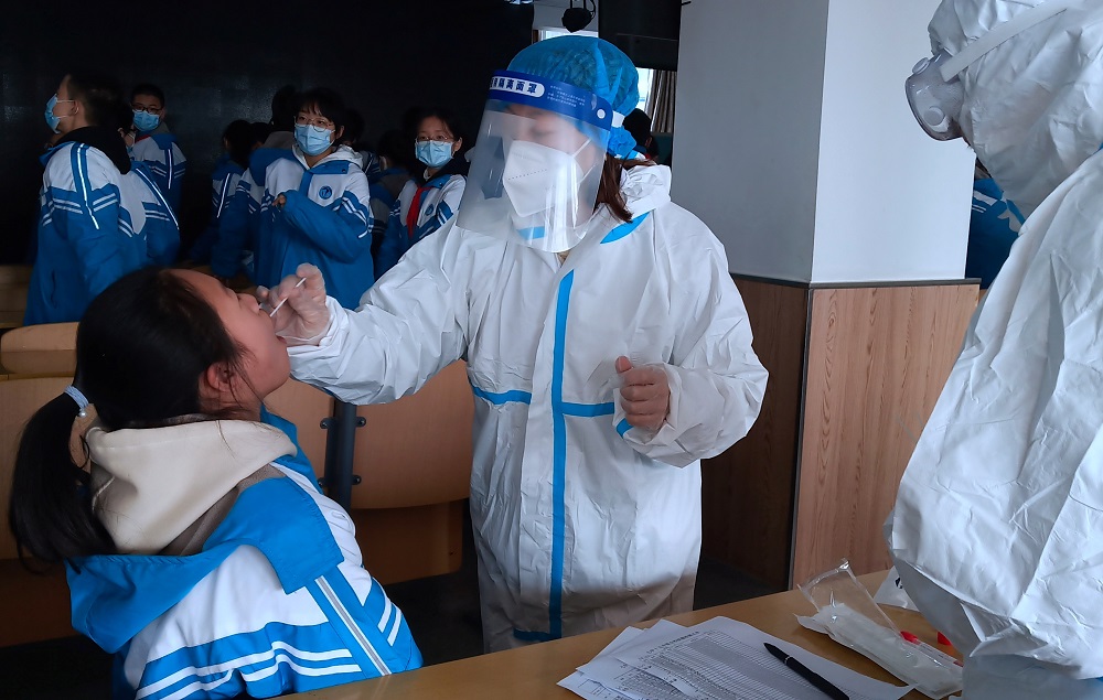 A medical worker in a protective suit collects a swab sample from a middle school student during a mass nucleic acid testing following a recent coronavirus disease outbreak in Xingtai, Hebei province, China January 6, 2021. u00e2u20acu2022 China Daily via Reuters pic