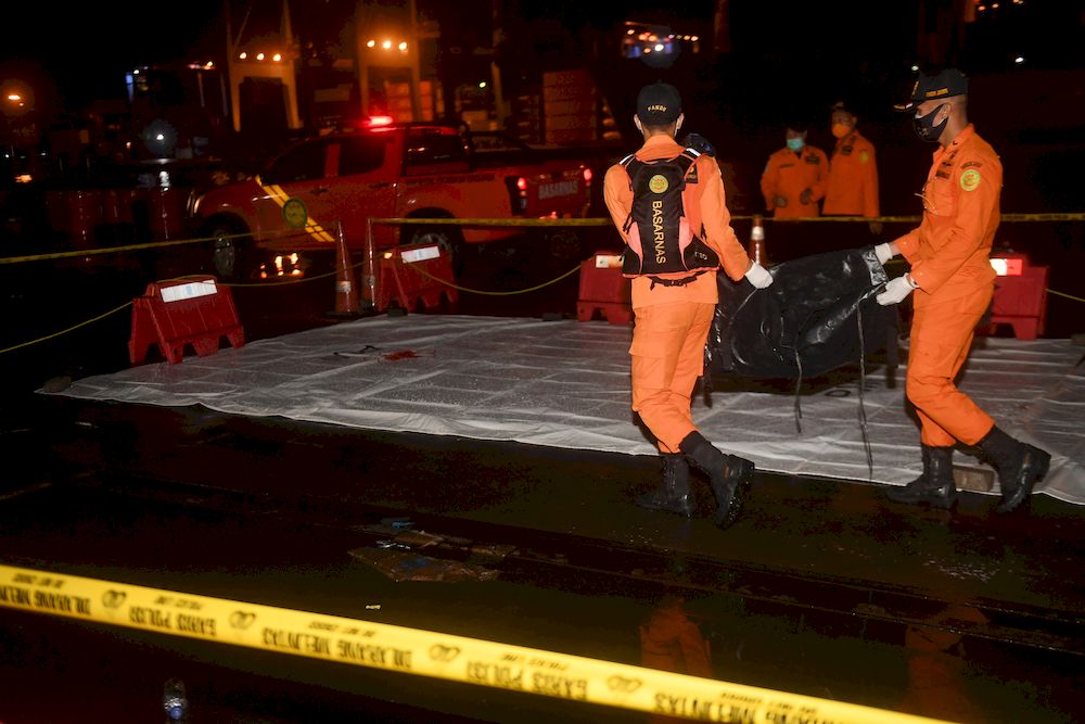 Indonesian rescue members carry a body bag containing suspected remains of the Sriwijaya Air plane flight SJ182 which crashed into the sea, at Jakarta International Container Terminal port in Jakarta, Indonesia, January 9, 2021. u00e2u20acu201d Antara Foto/Akbar Nugr