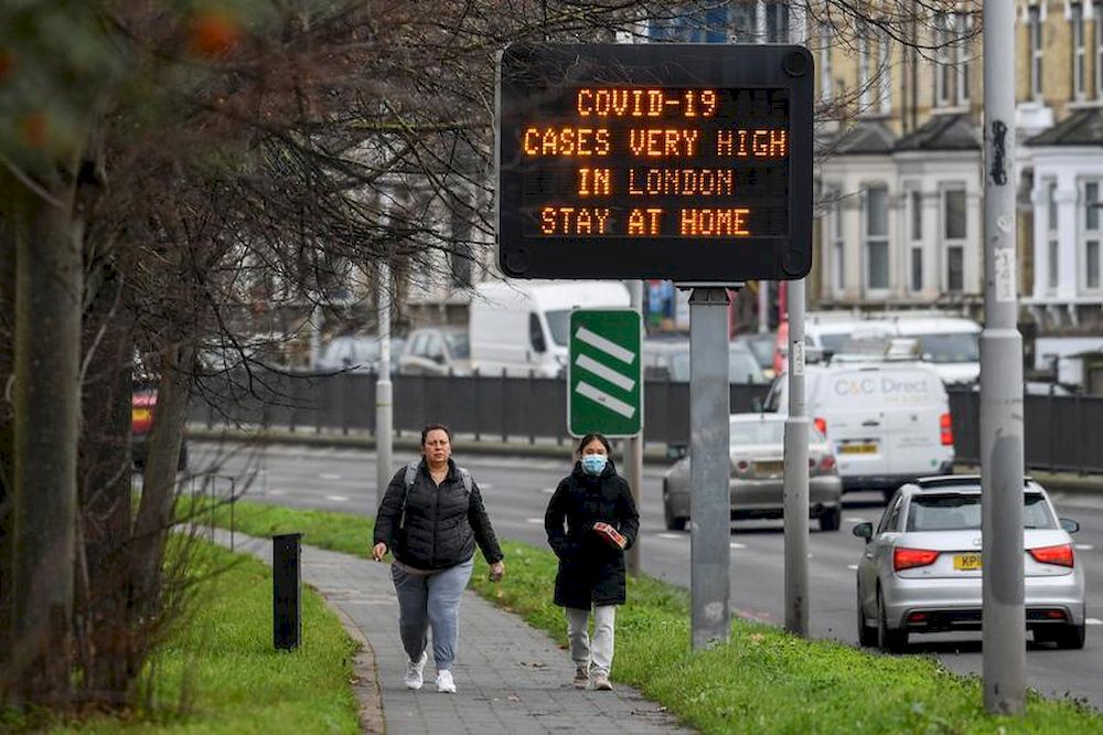 People walk past a roadside public health information sign, amidst the coronavirus disease (Covid-19) pandemic, in London, December 29, 2020. u00e2u20acu201d Reuters pic