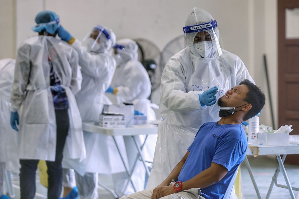 A healthcare worker collects swab samples to test for Covid-19 at Dewan Desa Temuan in Kota Damansara January 29, 2021. u00e2u20acu201d Picture by Ahmad Zamzahurinn