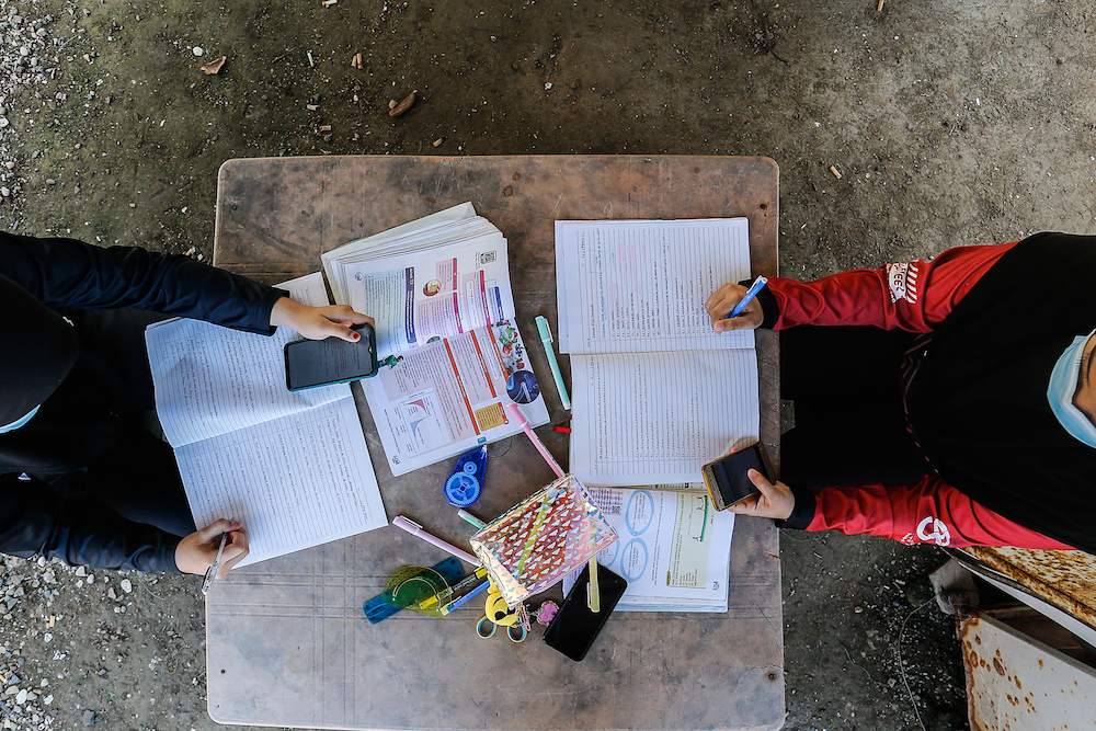 Nur Alea Soffiyyah Ahmad Hanif (left) and her schoolmate Hanis Syuhada Razali (right) attend online classes in front of their house on Pulau Aman January 22, 2021. u00e2u20acu201d Picture by Sayuti Zainudin