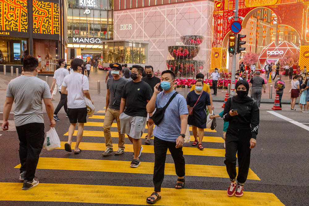People wearing facemasks cross the road in front of Pavilion in Bukit Bintang amid the movement control order in Kuala Lumpur February 16, 2021. u00e2u20acu201d Picture by FIrdaus Latif