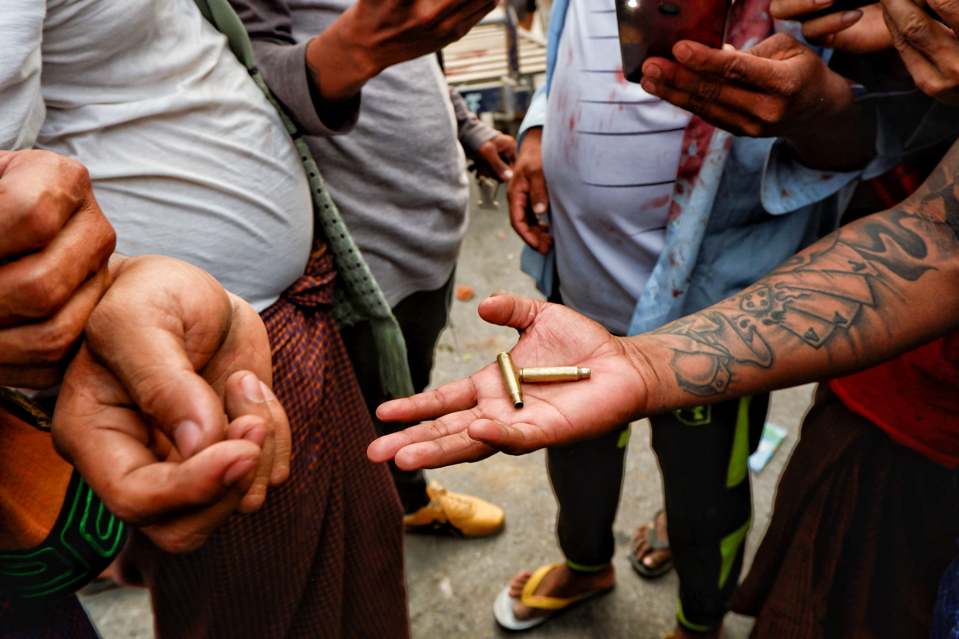 缅甸军队周六向示威者开枪后，有示威者捡拾散落在地上的子弹壳。-路透社-
